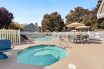A pool with a hot tub and chairs.